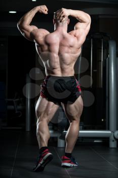 Young Man Standing Strong In The Gym And Flexing Muscles - Muscular Athletic Bodybuilder Fitness Model Posing After Exercises
