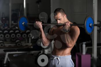 Athlete In The Gym Performing Biceps Curls With A Barbell