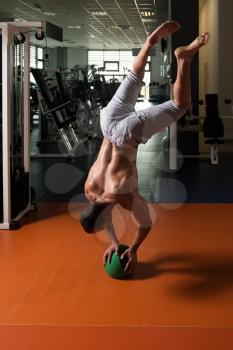 Athlete Doing Handstand Push-Ups On Medicine Ball As Part Of Bodybuilding Training In Gym