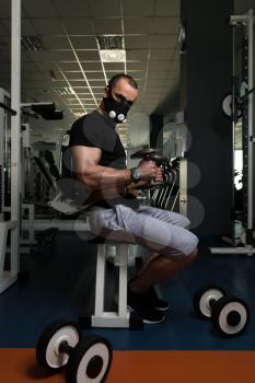 Man Working Out Biceps In Elevation Mask - Dumbbell Concentration Curls