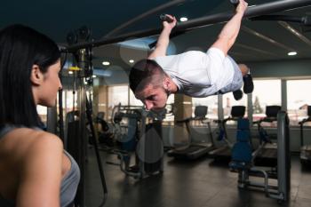 Personal Trainer Showing Young Woman How To Train Pull Ups - Chin-Ups In The Gym