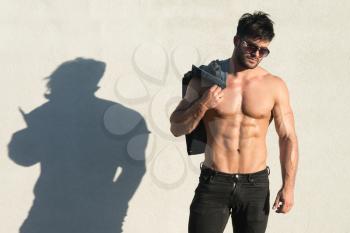 Healthy Young Man Standing Strong Flexing Muscles While Wearing Black Jeans - Muscular Athletic Bodybuilder Fitness Model Posing After Exercises Outdoors - a Place for Your Text