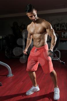 Man In The Gym Exercising On His Biceps On Machine With Cable In The Gym