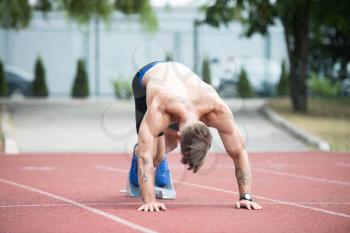 Athletic Man on Running Track Getting Ready to Start Run