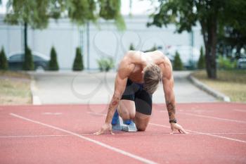 Fit and Confident Man in Starting Position Ready for Running