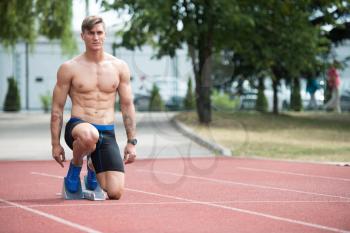 Athletic Man on Running Track Getting Ready to Start Run