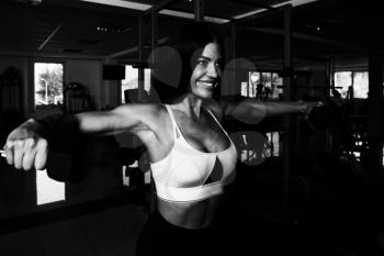 Muscular Fitness Woman Athlete Doing Heavy Weight Exercise For Shoulders With Dumbbells In The Gym