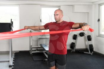Athlete in Sport Sportswear Workout With Elastic Resistance Band - Doing Shoulder Or Back Exercises in Gym
