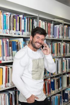 Portrait of a Happy Handsome Man Talking on Mobile Phone in Library at the University