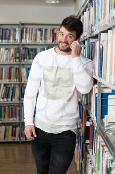 Young Bearded Student Talking Phone While Preparing for Exams in Univercity Library