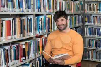 Handsome Male Student With Books Working in a High School Library