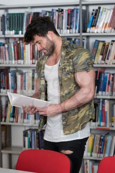 Handsome Muscular Man With Dark Hair Standing in the Library - Bodybuilder Preparing Exam and Learning Lessons in School Library