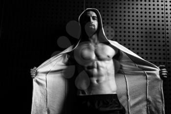 Portrait of a Young Physically Fit Man Showing His Well Trained Body In Hoodie - Muscular Athletic Bodybuilder Fitness Model Posing After Exercises on Wall Near the Wall - a Place for Your Text