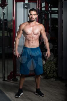 Healthy Young Man Standing Strong In The Gym And Flexing Muscles - Muscular Athletic Bodybuilder Fitness Model Posing After Exercises