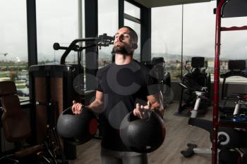 Man Working Out Biceps In A Gym With Medicine Balls