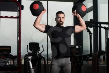 Man Working Out Shoulder In A Gym With Medicine Balls