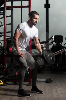 Muscular Man Doing Heavy Weight Exercise For Back With Barbell In Gym