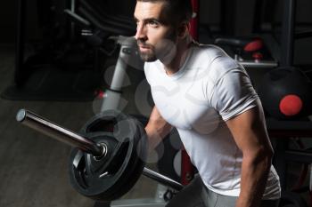 Muscular Man Doing Heavy Weight Exercise For Back With Barbell In Gym