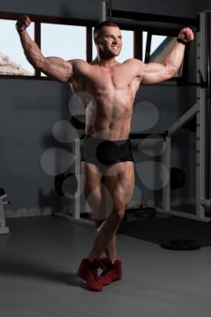 Handsome Young Man Standing Strong In The Gym And Flexing Muscles - Muscular Athletic Bodybuilder Fitness Model Posing After Exercises