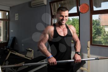 Muscular Man Doing Heavy Weight Exercise For Forearm With Barbell In Gym