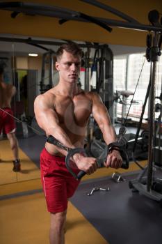 Handsome Muscular Fitness Bodybuilder Doing Heavy Weight Exercise For Chest On Machine With Cable In The Gym