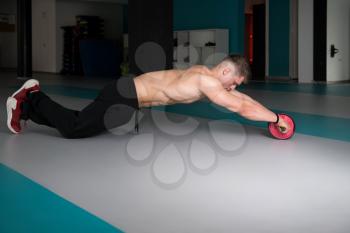 Young Man Exercising Fitness Workout For Abdominal With Toning Wheel