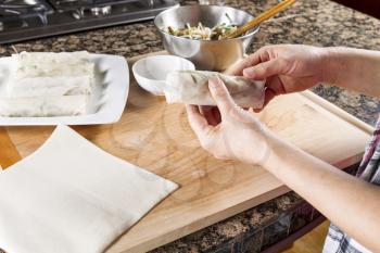 Horizontal photo of female hands making rolling wrap to make Chinese Spring Roll
