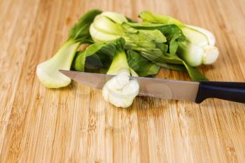 Closeup horizontal photo of washed Chinese Choy vegetable with cutting knife on natural bamboo wood