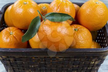 Closeup Horizontal photo of basket full of ripe oranges on faded wooden table