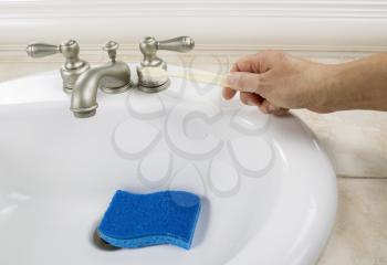 Hand holding cleaning brush near bathroom faucet