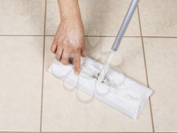 Hand placing paper wiper on cleaning broom for bathroom tile sweep