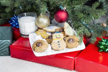 Homemade cookies on white plate with glass of milk for holiday gift to Santa