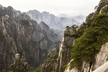 Deep valley in China's Yellow Mountains with cloudy sky in background 