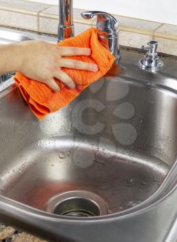 Vertical photo of female hand drying off kitchen sink with microfiber towel