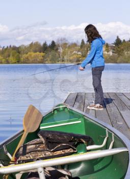 Fishing boat on dock with young girl fishing in background