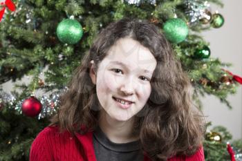 Closeup of young girl smiling with Christmas Tree in Background