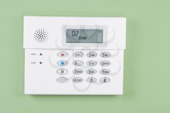 Home security alarm system activated on green wall background