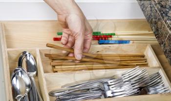 Female hand picking up wooden chop sticks out of kitchen drawer