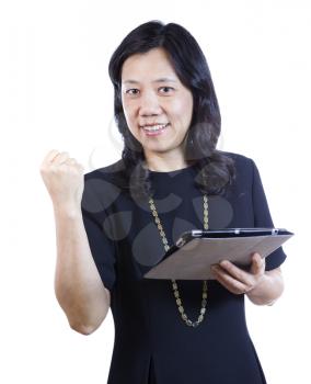 A vertical portrait photo of a mature Asian woman wearing a dark dress while holding a folder and raising her fist in joy on white background