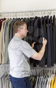 Vertical portrait of mature man in walk-in closet inspecting his sweater for daily wear