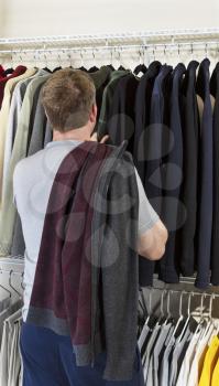 Vertical portrait of mature man in walk-in closet over looking his sweaters for wearing