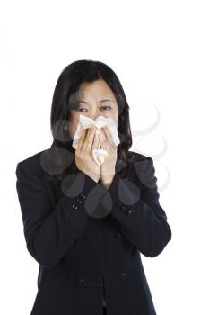 Mature Asian woman rubbing nose with tissue on white background