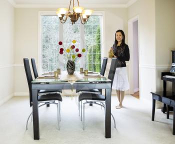 photo of mature woman bringing tea into family formal dining room with daylight coming through large windows in background