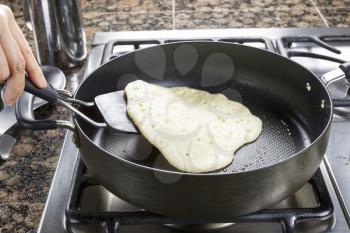 Horizontal photo of focus on pancake batter being fried into a pancake within hot frying pan