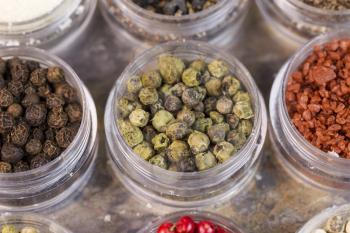 Horizontal top focus shot of green peppercorns in small container on stone surface