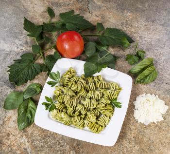 Freshly made Pesto Pasta with basil, parsley and tomato on stone background