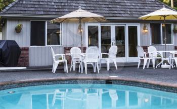 Pool house with pool, tables, chairs and umbrellas in foreground