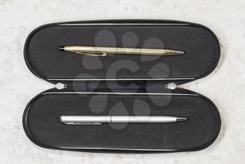 Gold and Silver pen set in black carry case on white stone background