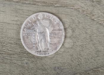 Old Liberty Silver Quarter Dollar on stressed wood background