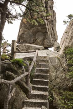 Small staircase in China's Yellow Mountain Trails with large rock and sky in background 
